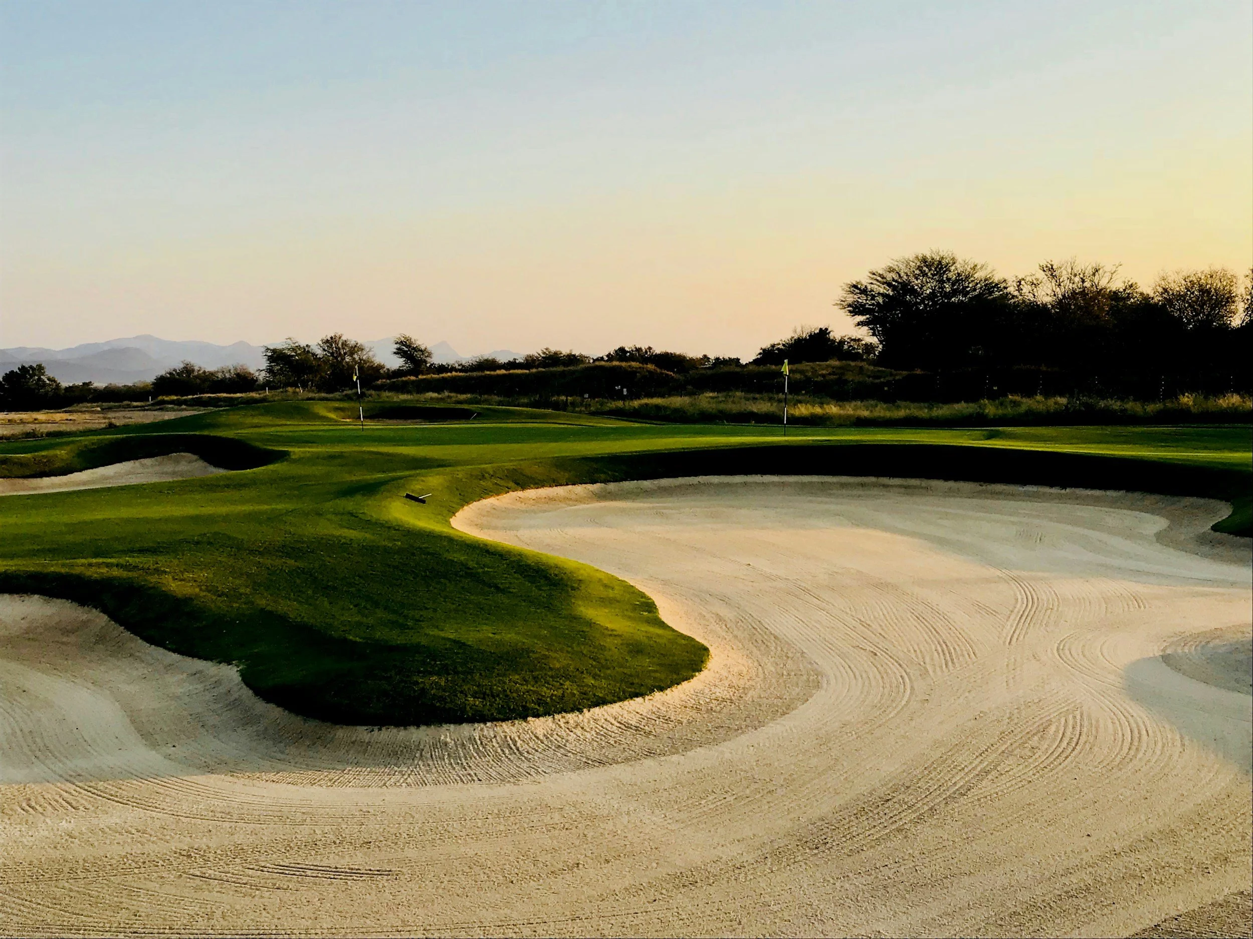 Practice greens and sculpted bunkers at sunset